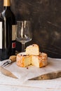 French munster cheese with orange rind, red pepper corns, cut off slice, fork,wine bottle and glass