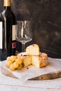 French munster cheese with orange rind, red pepper corns, white grapes cut off slice, wine bottle and glass