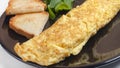 French omelet close-up on a black plate with lettuce