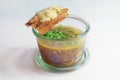 French onion soup with fresh green herbs in a glass jar and roasted bread with melted cheese, light gray background, copy space,