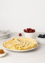 Stack french pancakes with berries and honey on a white plate, copy space