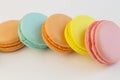 French pastry cookies cupcake macarons close-up. Macaroons multi color on a white background, yellow pink blue macaronis