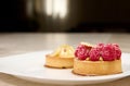 French patisserie. Still life with a delicious tartlet and raspberries with lemon on a white plate