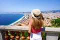 French Riviera. Back view of beautiful young woman holding hat enjoying the cityscape of Nice, France Royalty Free Stock Photo