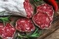 French salami with rosemary, chili pepper and peppercorns on wooden cutting board over rustic background Royalty Free Stock Photo