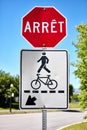 French stop sign arret and a pedestrian and bicycle sign near a road in Montreal, Canada