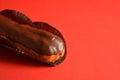 French traditional dessert eclair with dark chocolate on top filled with custard served on red background Royalty Free Stock Photo