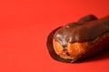 French traditional dessert eclair with dark chocolate on top filled with custard served on red background Royalty Free Stock Photo