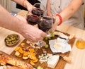 Frends eating cheese with grapes and drinking wine at home together, cheese party concept