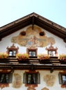 Fresco above windows with white curtains and wooden balcony in Oberammergau in Germany