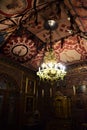 Frescoed ceiling and lighted chandelier of a colorful room with paintings on the walls of the villa museum of Frederick Stibbert.