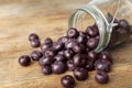 Fresh acai berries scattered from jar on table, closeup view. Space for text