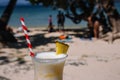 Fresh alcohol cocktail on the beach. Cold pina colada on seascape background. Cool pineapple cocktail with stick. Exotic resort.