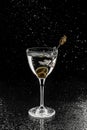 Fresh alcoholic cocktail with vodka and olive in wineglass on black background. Studio shot of drink in freeze motion, flying Royalty Free Stock Photo