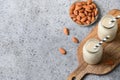 Fresh almond milk in glass bottle and almonds around on beige. View from above