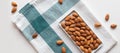 Fresh nut almonds in a ceramic bowl with a towel on a white background. Flat lay, top view, copy space Royalty Free Stock Photo