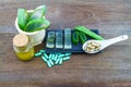 Fresh aloe vera gel on black ceramic dish with aloe vera essential oil and color pill on wooden table