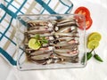 Fresh Anchovy Fish decorated with herbs and vegetables on a white background.