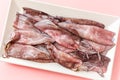 Fresh ancooked squids on white plate on pink background. Top view Royalty Free Stock Photo