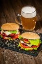 Fresh appetite homemade beef burgers on wooden table with glass of beer. Selective focus. Royalty Free Stock Photo