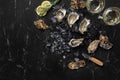 Fresh opened oysters, ice, lemon on a rectangle slate and champagne are on a black stone textured background. Top view Royalty Free Stock Photo
