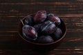 Fresh appetizing plums in a brown bowl, summer concept, copy space