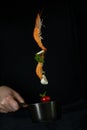 Fresh appetizing shrimp fall into a black pan on a dark background