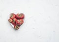 Fresh appetizing strawberry, in a white bowl in the shape of a heart, on a white rustic background, space for text top view