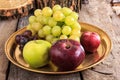 Fresh apples and grapes on golden plate over wooden background Royalty Free Stock Photo