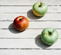 Fresh apples in the kitchen on the table, three apples. One red Apple and two green apples lie on a white wooden background Royalty Free Stock Photo