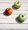 Fresh apples in the kitchen on the table, three apples. One red Apple and two green apples lie on a white wooden background Royalty Free Stock Photo