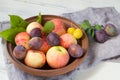 Fresh apples and plums in a clay bowl