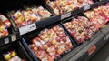 Fresh apples wrapped in cellophane on display in a supermarket.