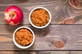 Fresh applesauce in bowls and red apples on a wooden table