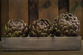 3 fresh artichokes green-purple flower head, on wooden background Royalty Free Stock Photo