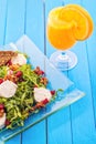 Fresh arugula salad with beetroot, goat cheese, bread slices and walnuts on glass plate on blue wooden background, product Royalty Free Stock Photo