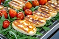 Fresh arugula salad with grilled halloumi and cherry tomatoes on a light textured background Royalty Free Stock Photo