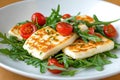 Fresh arugula salad with grilled halloumi and cherry tomatoes on a light textured background Royalty Free Stock Photo