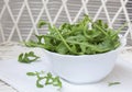 Fresh Arugula in White Bowl on White Wood