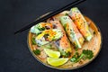 Fresh Asian appetizer Spring rolls Nem made from rice paper and raw vegetables and herbs with hot sauce on a dark background. Royalty Free Stock Photo