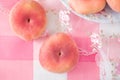 Fresh Asian peaches close-up on pink checkered tablecloth