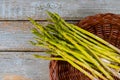 Fresh asparagus in brown basket on wood table