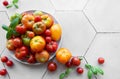 Fresh assorted tomatoes arranged on a white plate with green basil leaves in a bright kitchen setting Royalty Free Stock Photo
