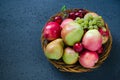 Fresh autumn fruits - ripe apples, pears, grapes and plums in a wicker wooden plate. Dark blue background. Harvest concept. Royalty Free Stock Photo