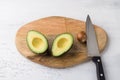 Fresh avocado cut in half and avocado pit with a knife on a wooden board on a light gray background, top view Royalty Free Stock Photo