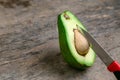 Fresh Avocado cut in half on wooden board with knife background