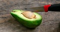 Fresh Avocado cut in half on wooden board with knife background Royalty Free Stock Photo