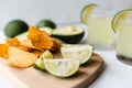 Fresh avocado, lime, drink and nacho chips lying on marble background. Recipe for Cinco de Mayo party Royalty Free Stock Photo