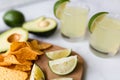 Fresh avocado, lime, drink and nacho chips lying on marble background. Recipe for Cinco de Mayo party Royalty Free Stock Photo