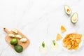 Fresh avocado, lime, drink and nacho chips lying on marble background. Recipe for Cinco de Mayo party. Top view, overhead, flat Royalty Free Stock Photo